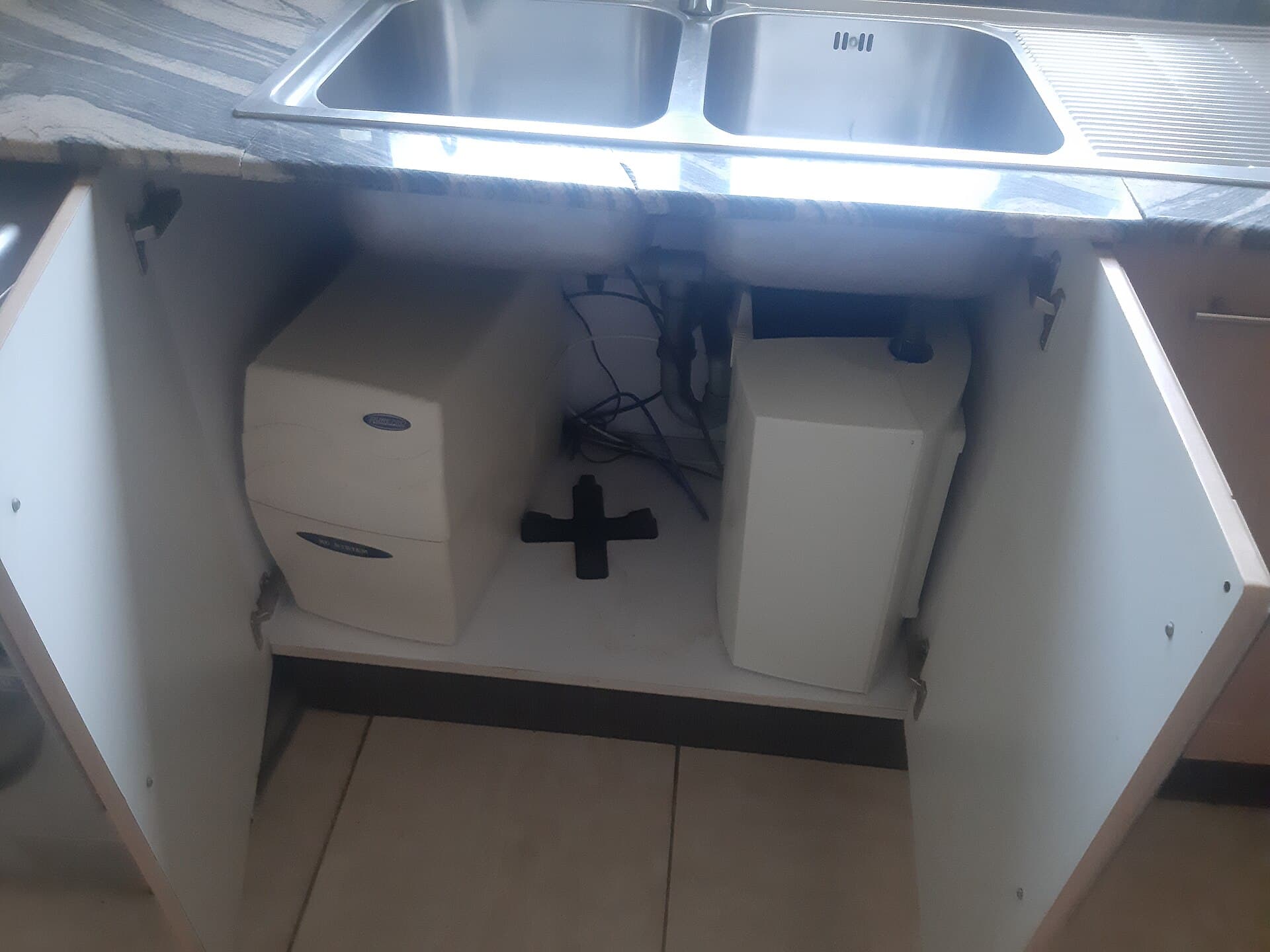 An under-sink water filtration system with filter housings installed in a cabinet